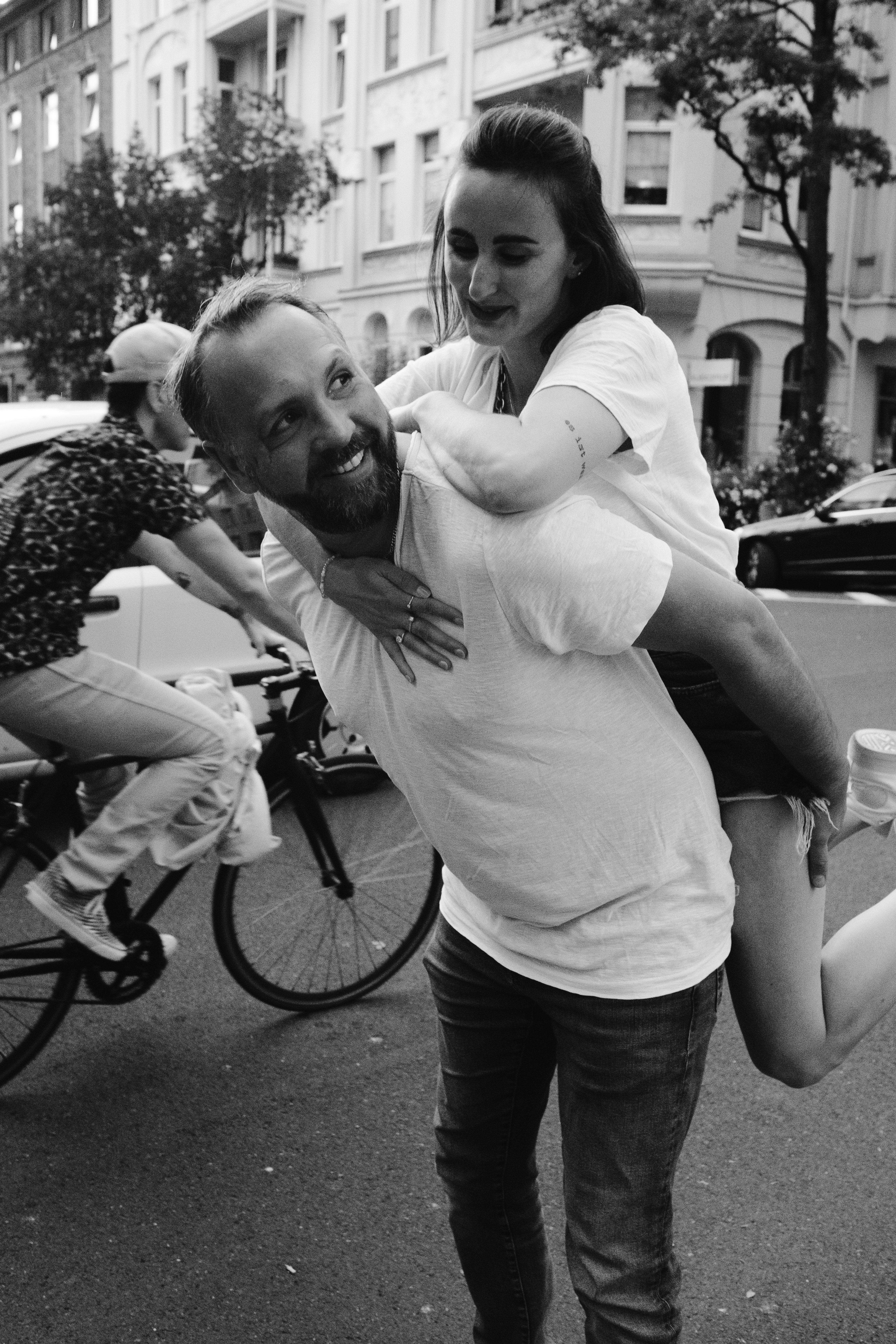 man in white shirt and black denim jeans holding girl in black and white photography